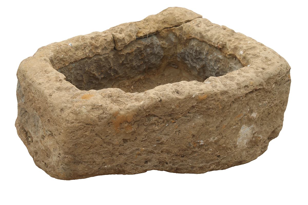 A reclaimed Northamptonshire sandstone trough showing a heavily weathered surface and hand carved chisel marks.