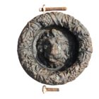 An antique cast iron lion head and garland door knocker showing weathering and detailed design.