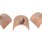 Three reclaimed decorative finial ridge tiles showing consistent weathering and rich terracotta colouring