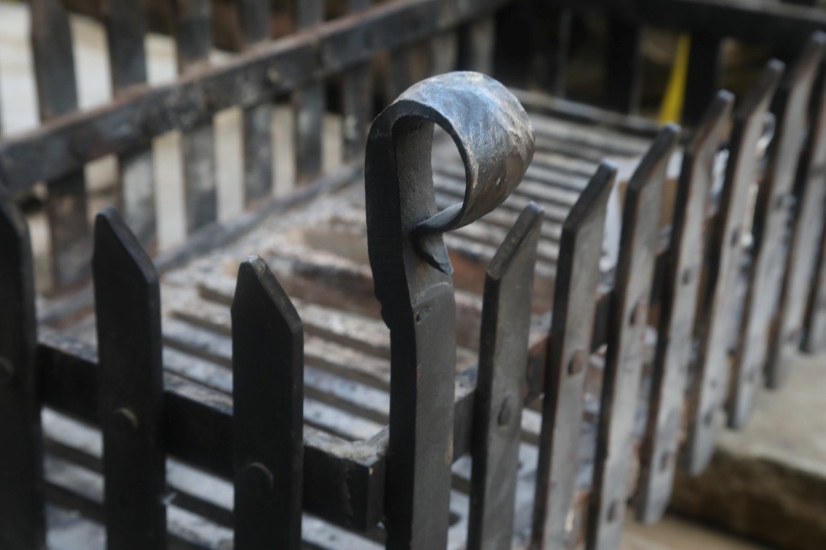 Reclaimed cast iron fence style fire basket detail showing the shepherds crook motif on the corner finial