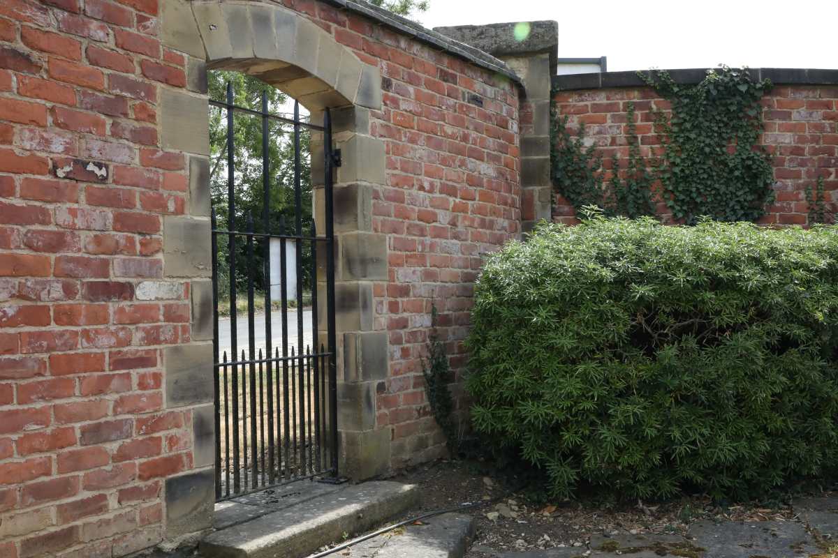 A large garden wall with entrance gate showing the use of reclaimed bricks and lime mortar