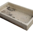 A shallow Butler sink with cream glaze and the weathered patina of age, use and reclamation