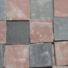 Reclaimed red and black quarry tiles in a classic chequerboard pattern and showing the remnants of mortar and dust from the process of reclamation.