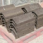 A pallet of reclaimed Universal angle concrete ridge tiles showing the weathered surfaces