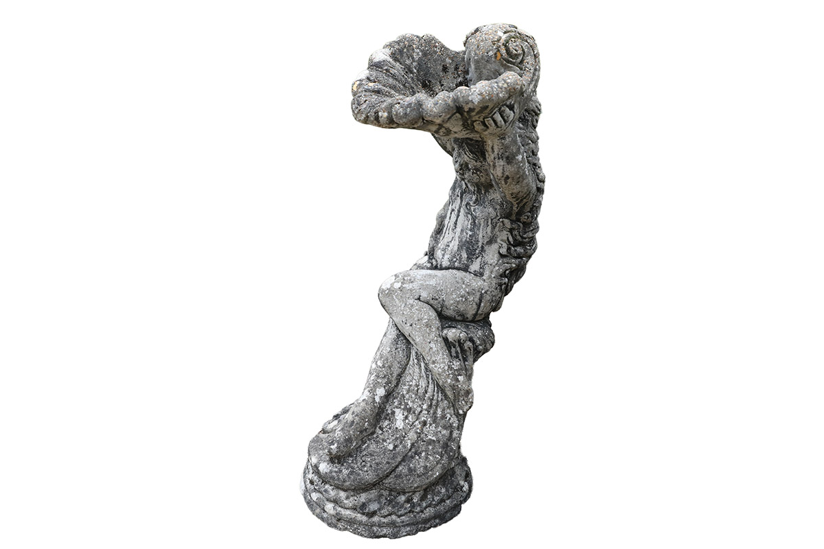 A composite stone birdbath depicting a cherub holding a shell and displaying a fabulous weathered patina