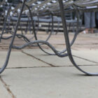 Detail of the elegant scrollwork on the zinc plated 3 seater garden bench with hand etched antique finish
