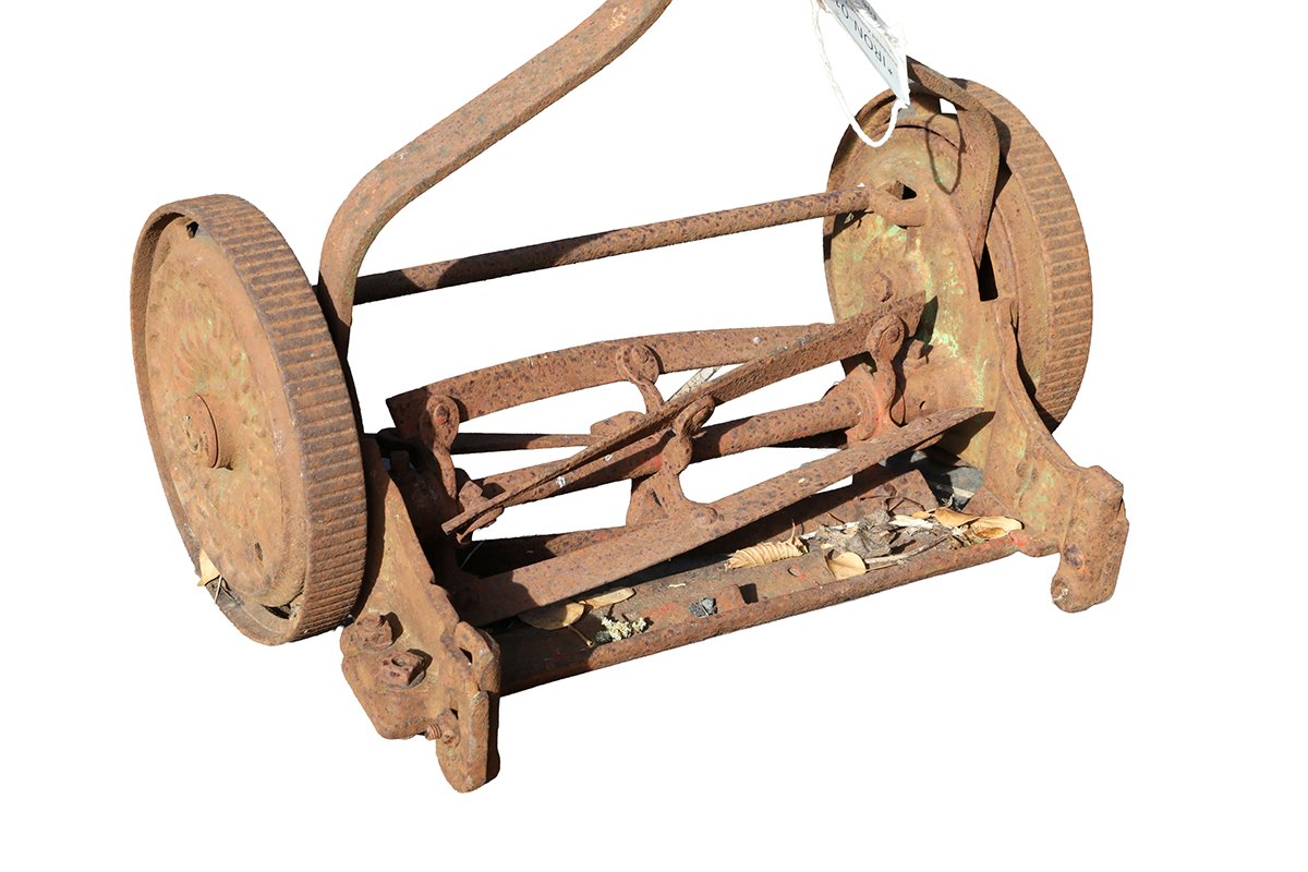 Detail of an antique push mower from the early 1900's, named The Trojan, showing heavy surface weathering