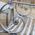 Detail of the zinc plated coffee table set with 4 chairs, showing the elegant scrollwork and relaxed attitude.