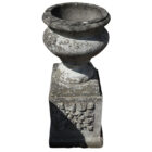 A weathered composite stone urn on pedestal, with an aged patina and standing 37 inches high