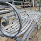 Detail of the impressive four seater zinc plated garden bench from The Suffolk Collection, showing the hand etched finish and elegant scrollwork