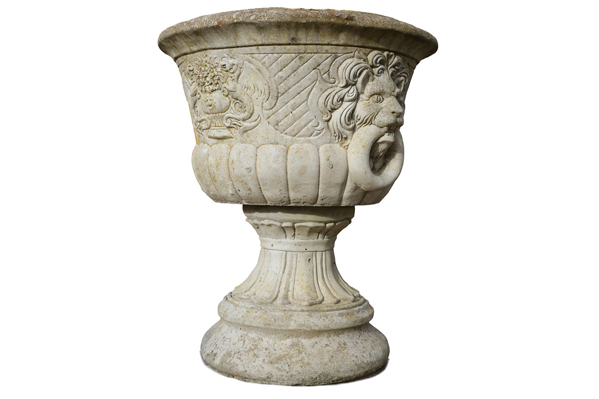 One of a pair of lions head urns in composite stone stone, showing a fine patina of weathered surfaces and spots of lichen.