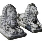 A pair of classical recumbent lions with a weathered patina and exuding a quiet strength