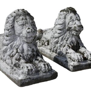 A pair of classical recumbent lions with a weathered patina and exuding a quiet strength