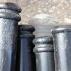 A mix of aluminium and cast iron reclaimed street bollards, painted black and showing some signs of weathering