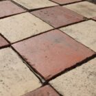 Detail of reclaimed red and buff quarry tiles showing an aged patina of surface wear and mortar remnants that brings a depth of character and visual appeal