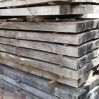 A stack of seasoned unused oak sleepers showing the weathered appearance from years of storage