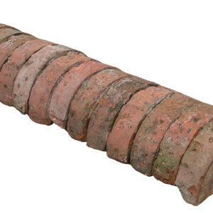 A run of antique red half round wall copings showing natural weathering and remnants of lime mortar