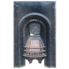 A reclaimed cast iron bedroom fireplace insert with a decorative arch design.