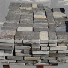 A pallet of reclaimed and weathered blue buff limestone setts showing tumbled and worn edges and a fabulous patina
