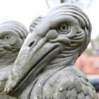 Detail of lightly weathered composite stone pelican statues with a stylised look and solid visual presence