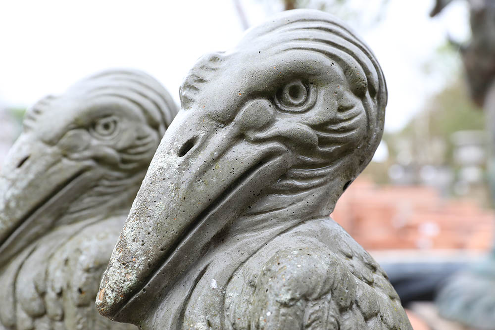 Detail of lightly weathered composite stone pelican statues with a stylised look and solid visual presence