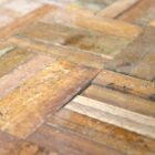 Detail of reclaimed oak finger parquet flooring showing its aged patina of varnish, various marks and remnants of prior installation