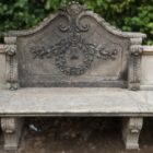 The intricate detail of a magnificent hand carved stone garden seat with a lush patina showing its years spent exposed to the British weather