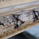 Detail of a 19th century hand carved fire surround with highly detailed design motifs and burnished pine finish