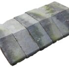 A short run of reclaimed bullnose edge saddleback wall copings showing a light patina of aged discolouration, lichen growth and green algae.