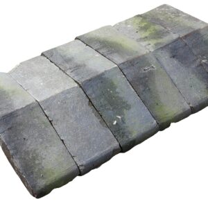 A short run of reclaimed bullnose edge saddleback wall copings showing a light patina of aged discolouration, lichen growth and green algae.