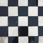 A batch of reclaimed commercial kitchen flooring made up of 10cm square ceramic tiles and showing the classic chequerboard pattern