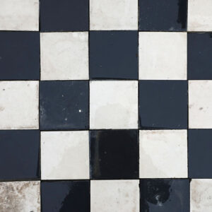 A batch of reclaimed commercial kitchen flooring made up of 10cm square ceramic tiles and showing the classic chequerboard pattern