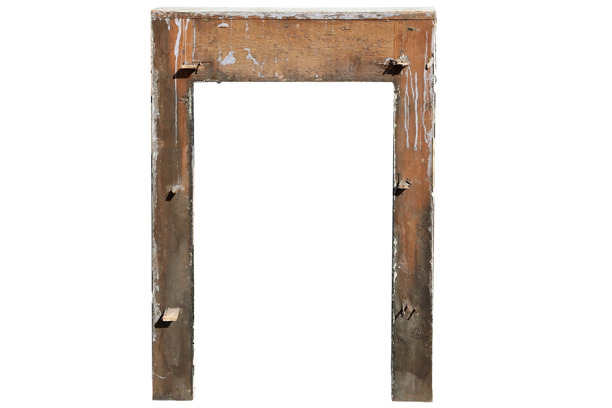 Reverse side of a white painted reclaimed pine fire surround showing its age through peeling paint and worn edges