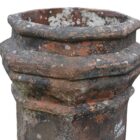Detail of the banding on a heavily weathered red octagonal chimney pot displaying a great patina of old soot staining and lichen.