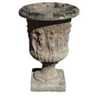A beautifully weathered, reclaimed, composite stone urn with a dancing maidens decorative motif.