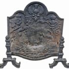 A heavily weathered, cast iron fire back with basket and dogs commemorating an historic battle in the North of England