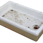 A large reclaimed butler sink with white ceramic rim and basin with buff fireclay base and drainage hole placed centrally at one end.