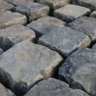 A spread of reclaimed black basalt setts in brick bond pattern, showing the worn faces of pre-loved paving