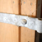 A detail of the durable hinge on a reclaimed softwood stable door with galvanised fittings and stainless steel kick/bite plate