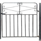 A reclaimed wrought iron gate with peeling black paint revealing patches of surface corrosion