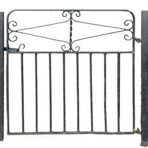 A reclaimed wrought iron gate with peeling black paint revealing patches of surface corrosion