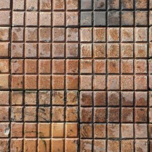 A small area of laid reclaimed and very rare Victorian salt glazed stable pavers, showing the unusual 10 bar design and rich colour of orange, russet and brown hues of the salt glaze firing process.