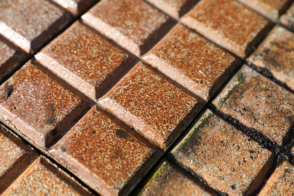 A close up of the fabulous finish on these reclaimed and very rare Victorian salt glazed stable pavers, showing the unusual 10 bar design and rich colour of orange, russet and brown hues of the salt glaze firing process.