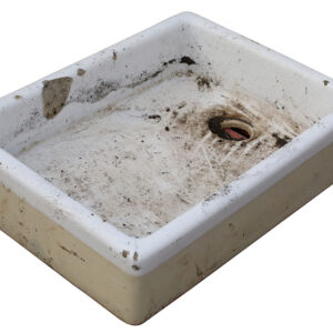 A reclaimed small white Butler sink with signs of age and prior use, with chips and marks around the rim and a buff coloured base