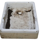 A reclaimed small white Butler sink with signs of age and prior use, with chips and marks around the rim and a buff coloured base