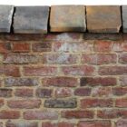 Reclaimed Staffordshire blue, square edge saddleback wall coping in situ, with a weathered patina of discolouration and small chips and marks