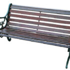A weathered vintage wooden bench with cast iron lion head ends