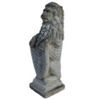 A reclaimed composite stone statue of a lion holding a shield with a weathered patina and classic pose